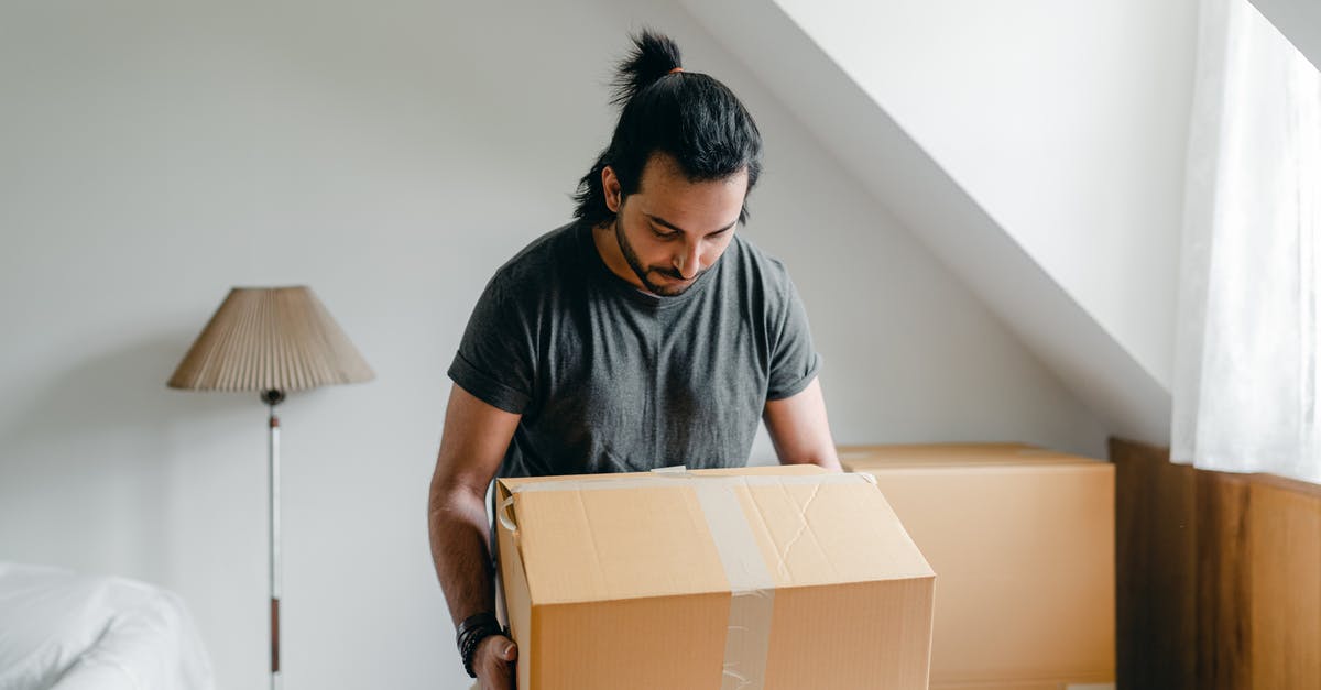 New passport, old one not expired - Ethnic guy picking up cardboard box in house