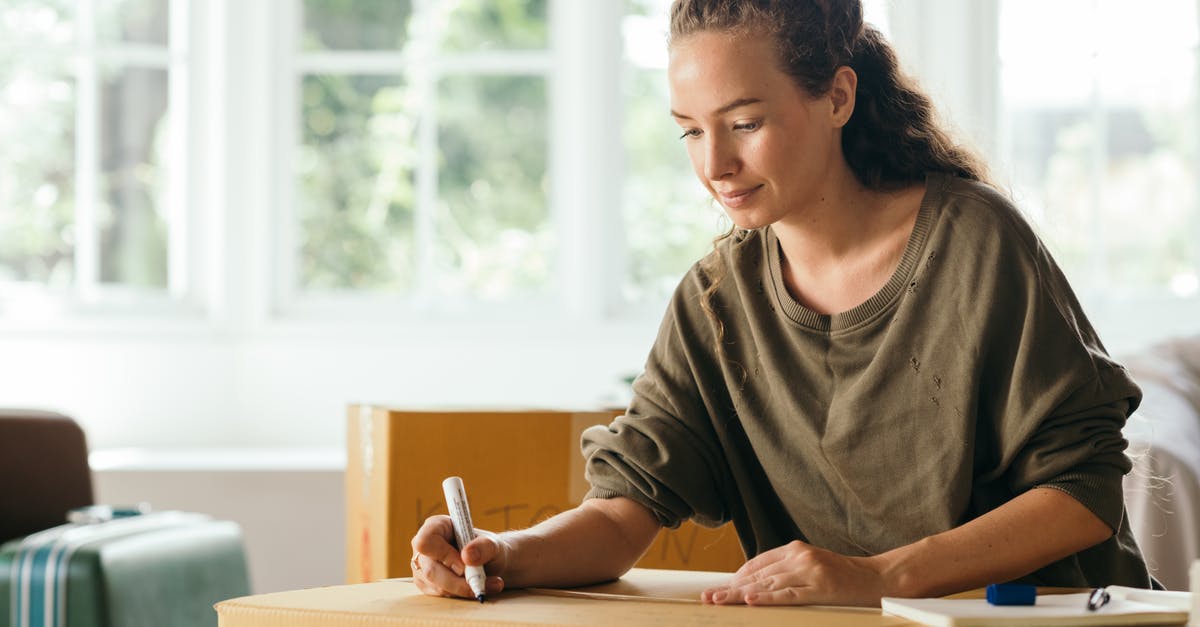 NEXUS eligibility after moving out of the US - Calm lady sitting on sofa and signing box with belongings in cozy house in sunny day while moving out