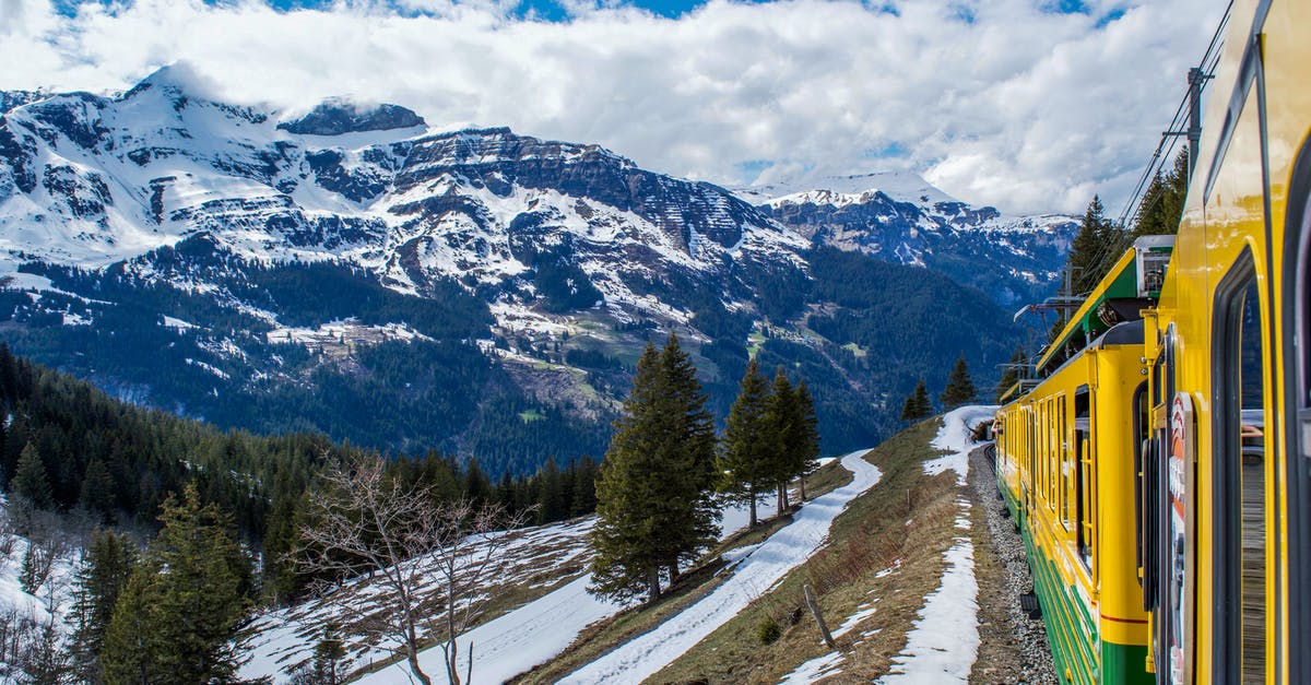 Nice paraglide spots nearby Geneva (Switzerland) by public transport - Modern train riding on railroad through coniferous woods in snowy mountainous valley in Switzerland