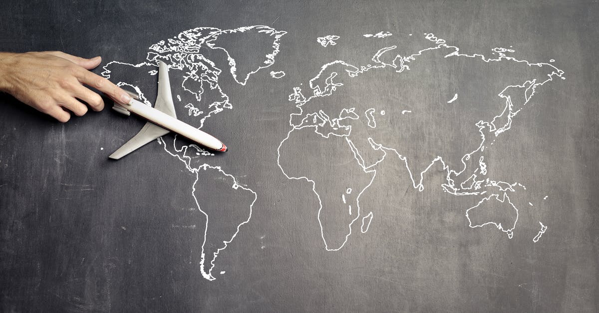 No Portland to Detroit direct flight? - From above of crop anonymous person driving toy airplane on empty world map drawn on blackboard representing travel concept