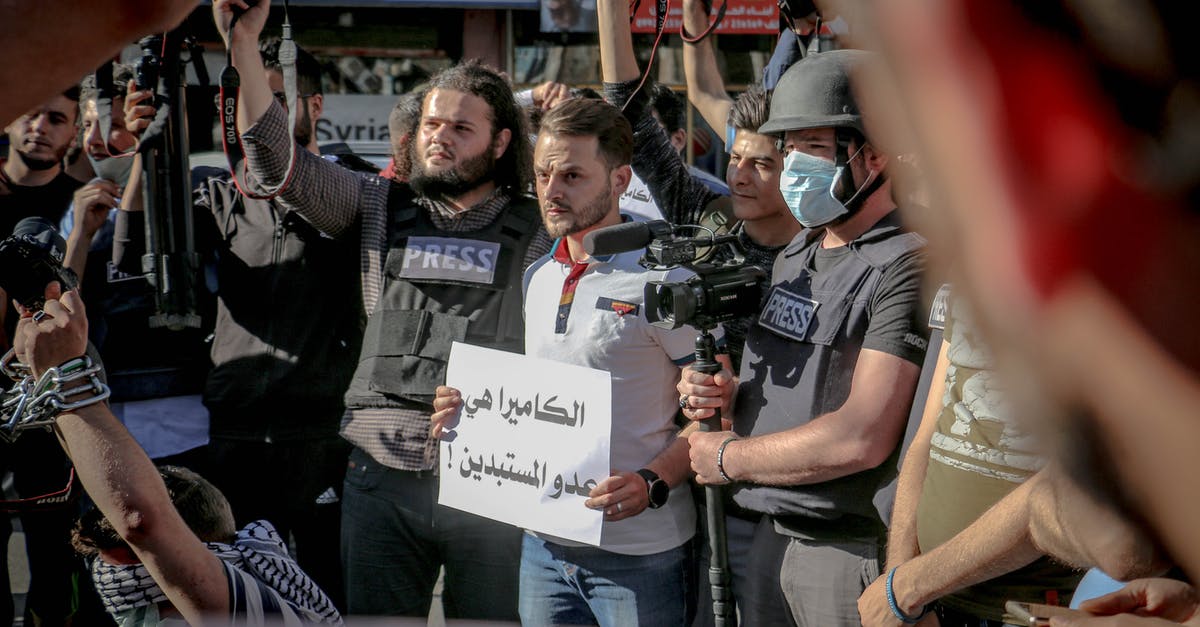 No refund cancellation policy and CoViD-19 - Group of ethnic journalists with placard with Arabic inscription and cameras at demonstration against policy