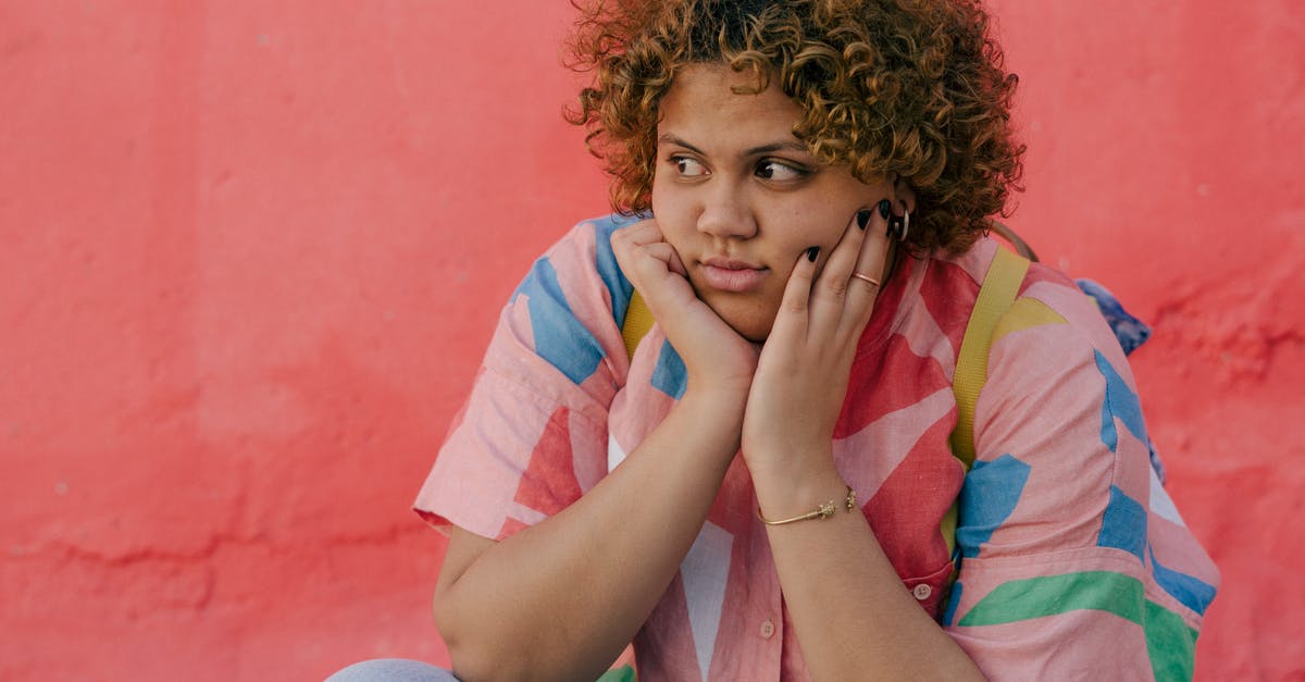 Norway - Why do all the school children wear red jumpsuits? - Thoughtful young ethnic plump lady in colorful clothes sitting in street near pink wall