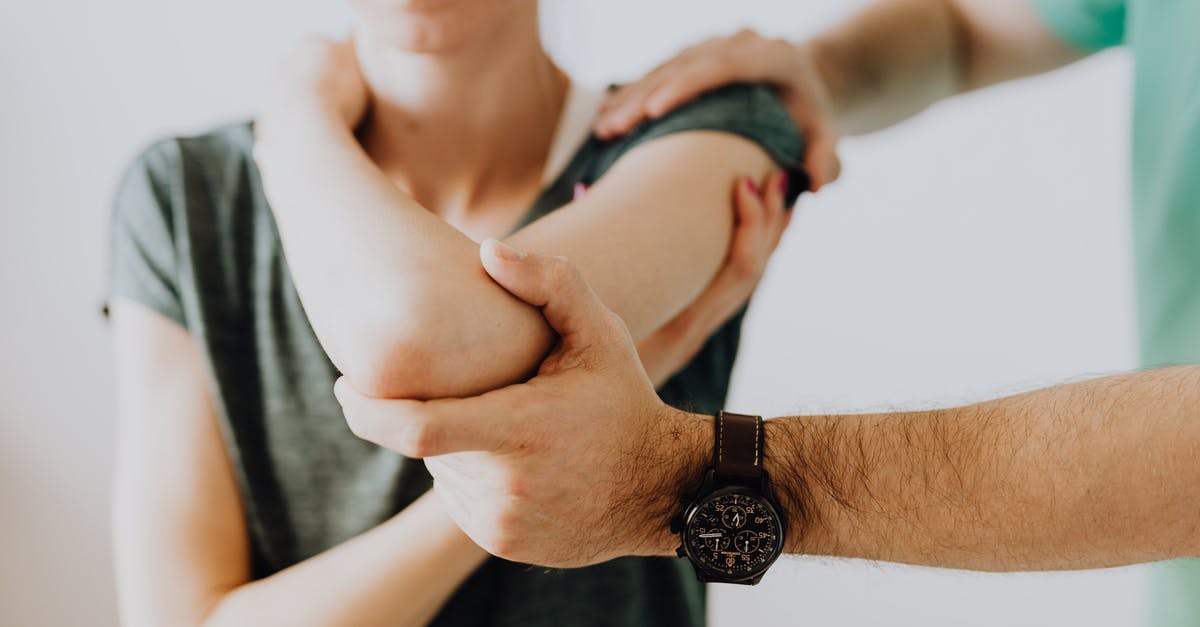 Notify border control on additional visits - Crop unrecognizable chiropractor examining arm joint of female patient