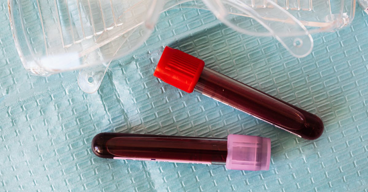 Obtaining a covid test in Czech Republic - Top view closeup of protective plastic eyeglasses and full of blood vials placed on medical diaper