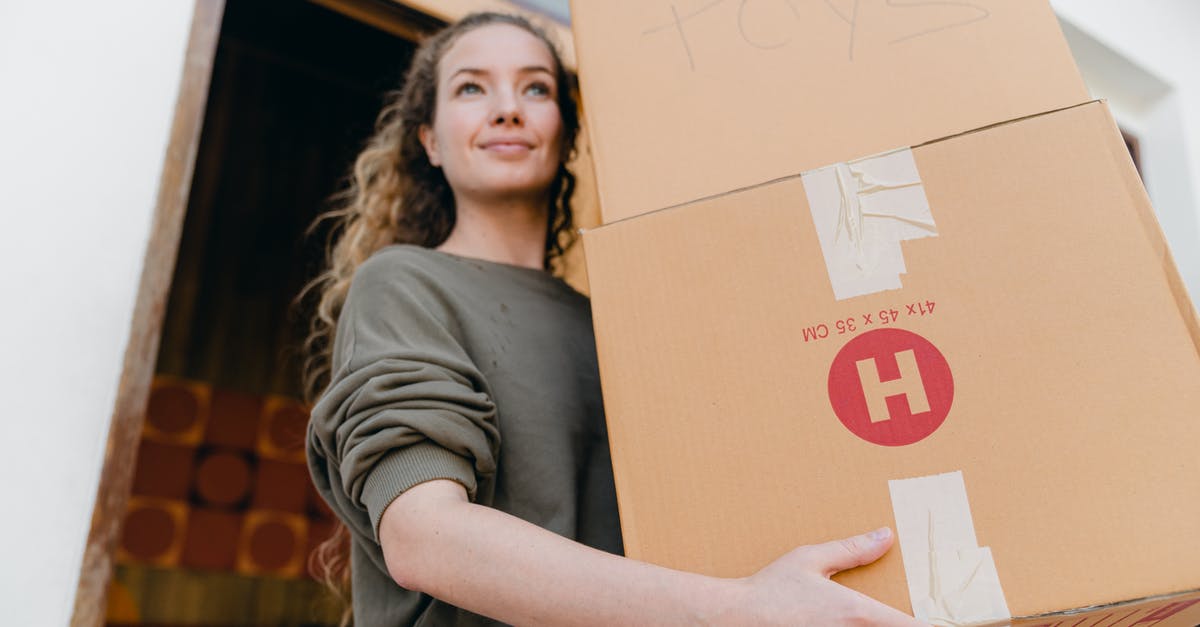 Obtaining a "Supervisa" for Canada from outside your home country? - Confident young lady in casual wear carrying heavy carton boxes with toys and looking away while leaving old house