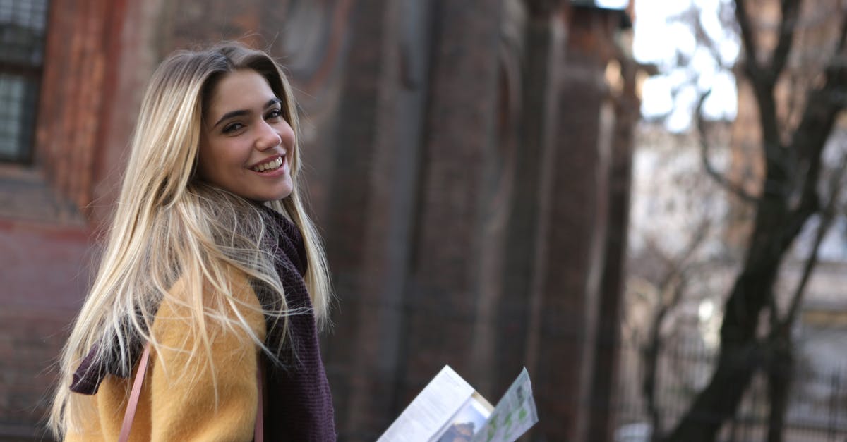 Obtaining paper map when arriving into the city - Woman in Brown Coat Holding White Printer Paper