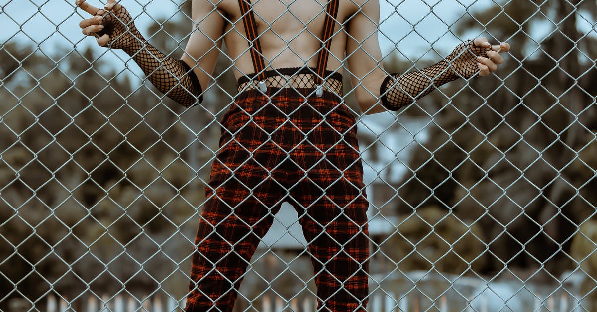 Odd, funky festivals in the Northeast of the US? - Crop faceless shirtless man in checkered trousers behind net fence