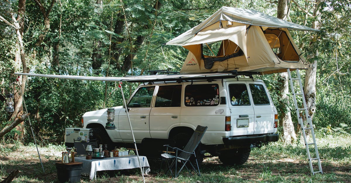 Offroad / 4x4 car rental with camping equipment in Morocco [closed] - White off road car with camping tent on top parked in lush green forest near small table with various food and utensils during picnic on sunny day