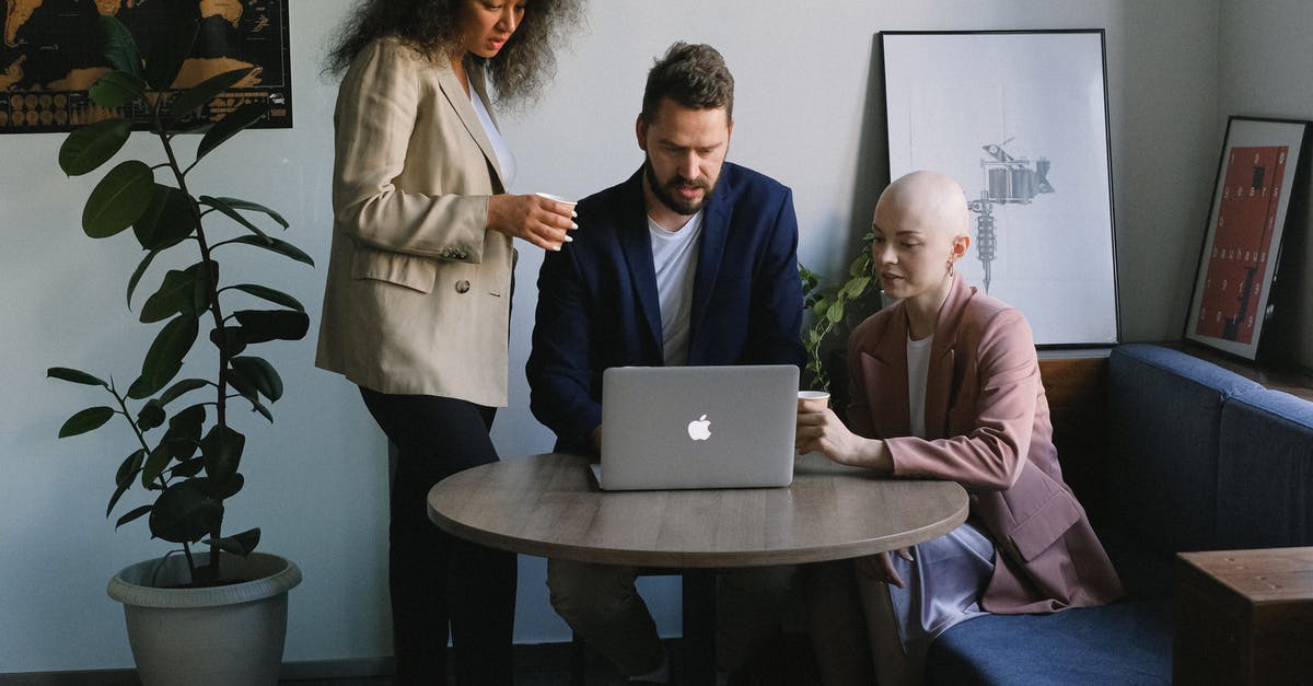 Online check in with group. How will the boarding passes be distributed? - Group of diverse colleagues discussing job while surfing internet on netbook at table of comfortable office