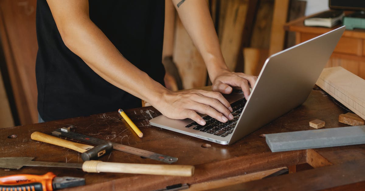 Online cruise search tool allowing to exclude some ports - Crop anonymous male searching information on internet on wooden table among carpentry tools in workshop