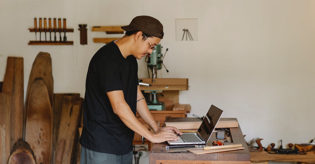 Online cruise search tool allowing to exclude some ports - Concentrated ethnic guy browsing laptop in woodworker workshop