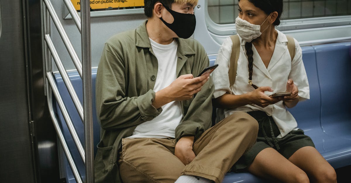 Online resource for reconnecting with other travelers? - Unrecognizable young Asian man and ethnic woman in face masks and casual clothes using mobile phones and chatting while riding train