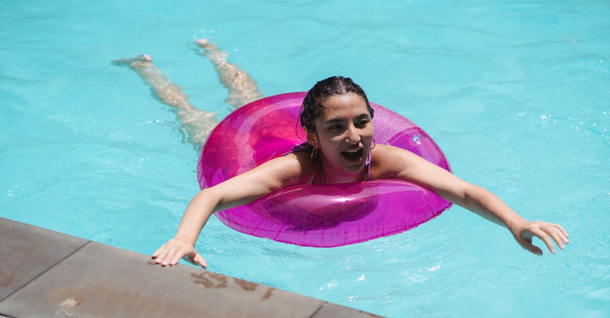 Open water swimming in the Saarland? - Cheerful young ethnic woman floating in pool in swim tube