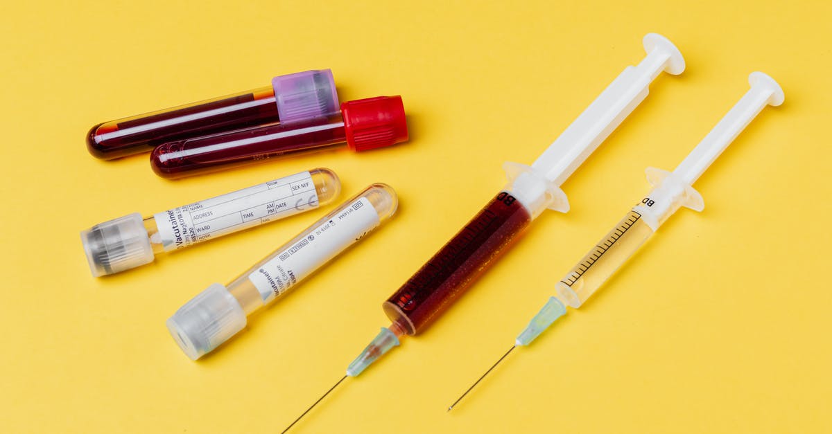 Oslo Airport COVID Test Time - From above of medical syringe with medication near injector with blood sample arranged with filled clinical test tubes placed on yellow background