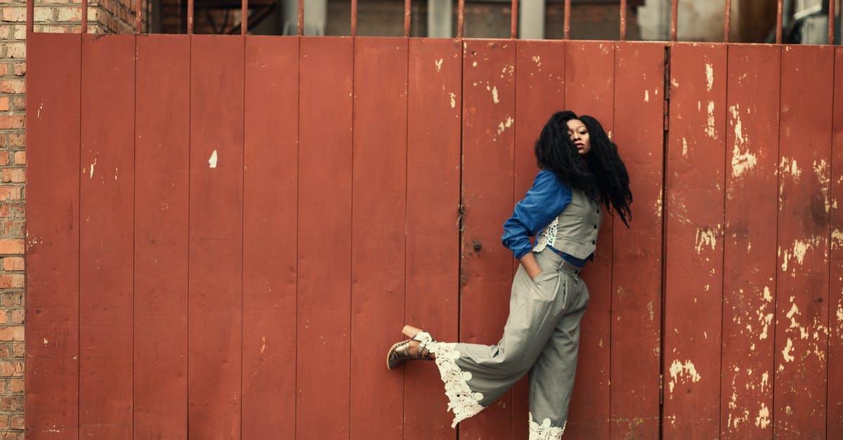 Outdoor clothing and shoes brands that people wear in Iceland [closed] - Woman Wearing Grey Jumpsuit Standing Beside Brown Metal Gate