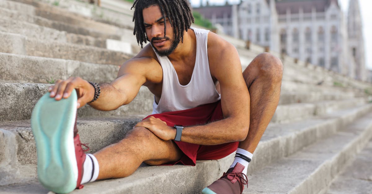 Outdoor clothing and shoes brands that people wear in Iceland [closed] - Man in White Tank Top Sitting on Concrete Stairs