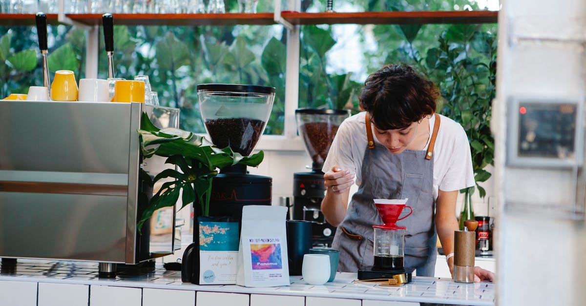 Over the counter pain killers in SE Asia? - Thoughtful female barista with brown hair in apron pouring aromatic alternative coffee while working in light cafe in daytime