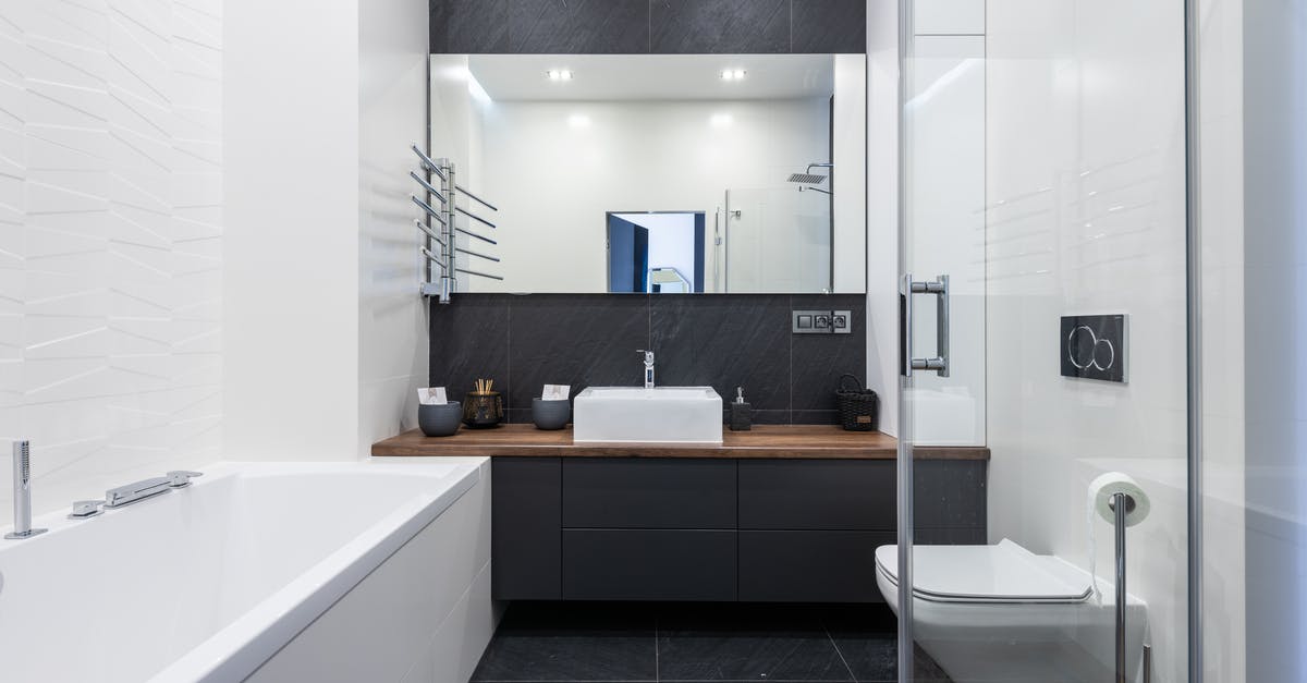 Overnight wifi/shower facilities in Haneda airport? - Interior of modern bathroom with bathtub near transparent shower cabin and toilet placed near black cupboard with sink and mirror