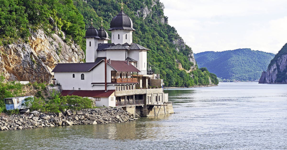 Overstay in Serbia - White and Black House Located at Riverside on Mountain Slope at Daytime