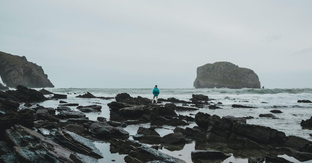 Overstay in Spain on my tourist visa [closed] - Anonymous man recreating on rocky coast of wavy ocean against misty sky