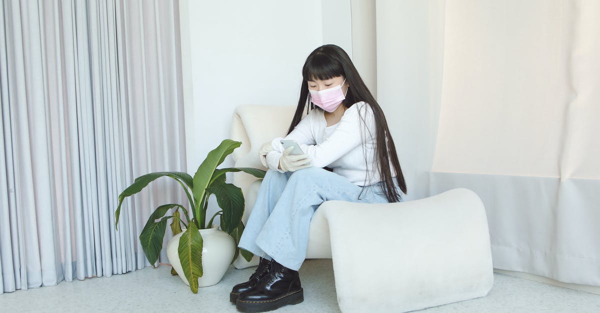 Overstaying Ukrainian visa due to Coronavirus - A Woman in White Sweatshirt and Denim Jeans Sitting on the Chair while Using Her Mobile Phone