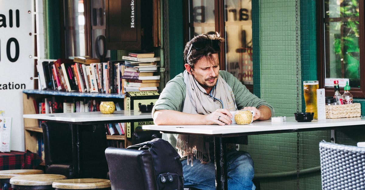 Owl Cafe in Tokyo where English is spoken? - Man Sitting in a Cafe and Using Smart Phone 