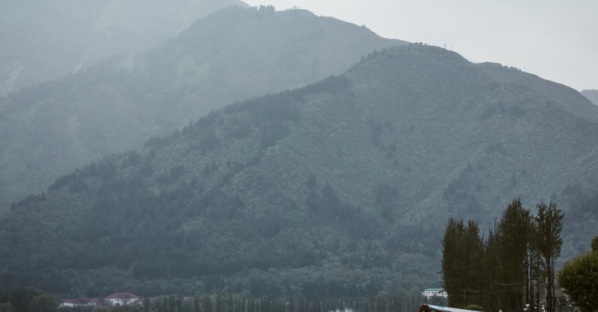 Pakistani travelling to Indian Kashmir? - Mountains in fog against lake with roofed boats