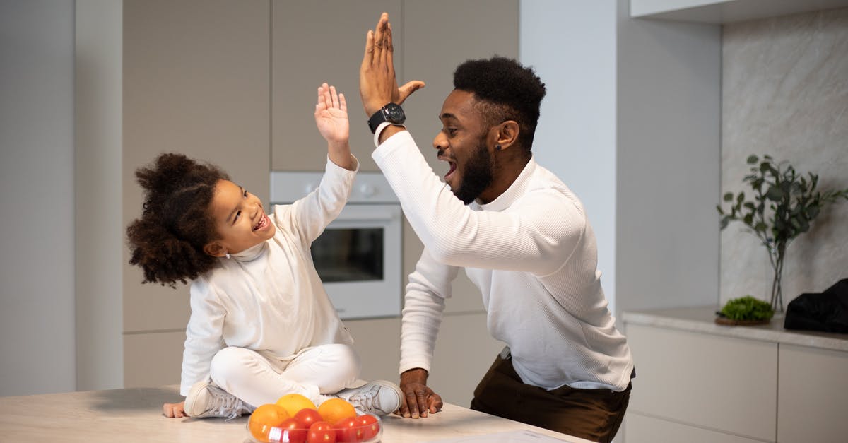 Parent-child; sit next to each other on an all-inclusive flight? - Joyful black father giving high five to adorable daughter