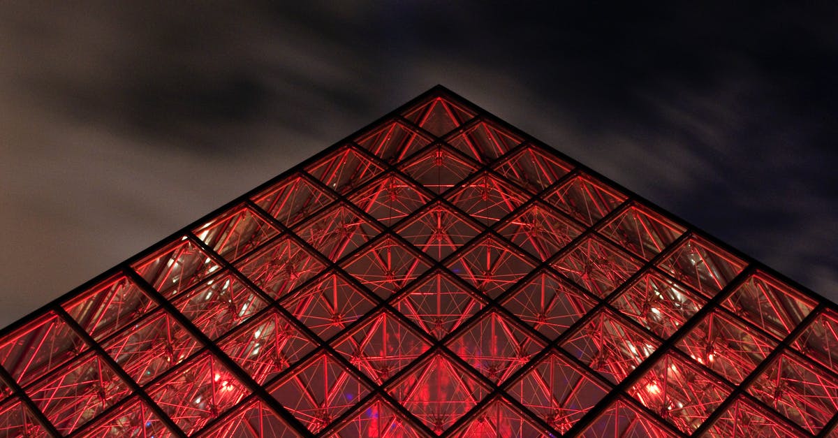 Paris & a cruise? [closed] - Close-up of the Tip of the Louvre Pyramid Illuminated in Bright Red Color 