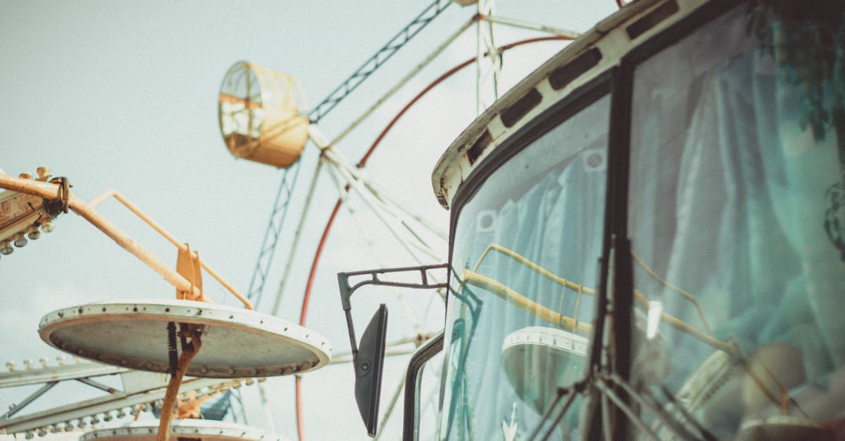 Park accessible by public transport in Eastern Canada in October - Modern bus parked against Ferris wheel and cloudless blue sky in amusement park in city