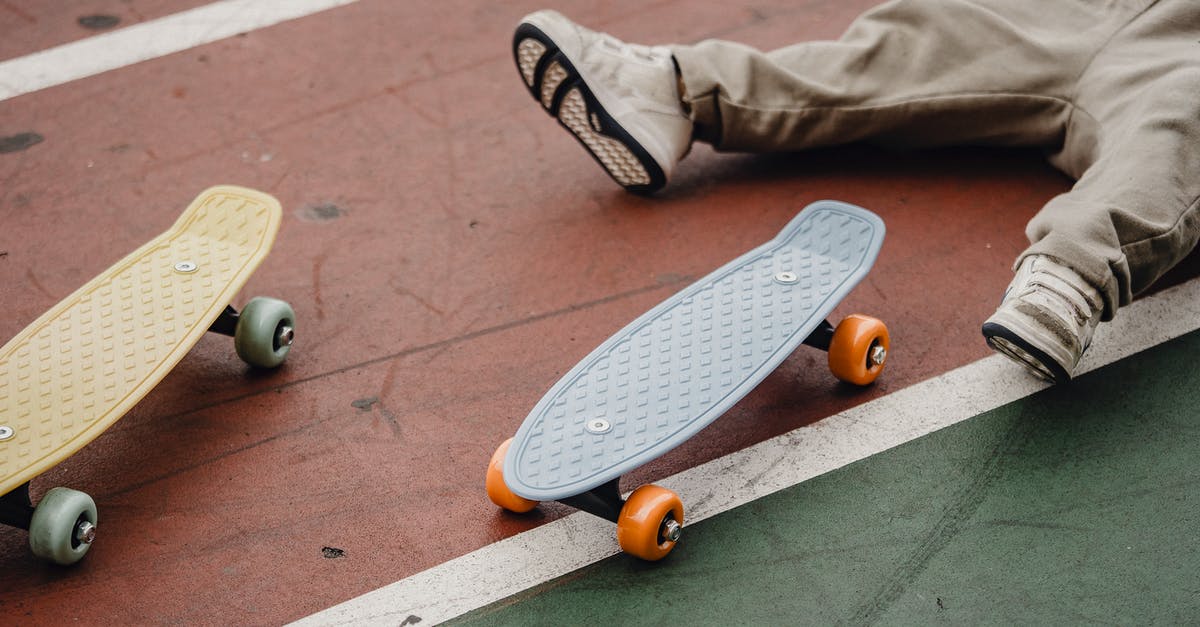 Park & Ride in Düsseldorf, coming from Belgium/Netherlands - Crop unrecognizable kid lying on ground near skateboard