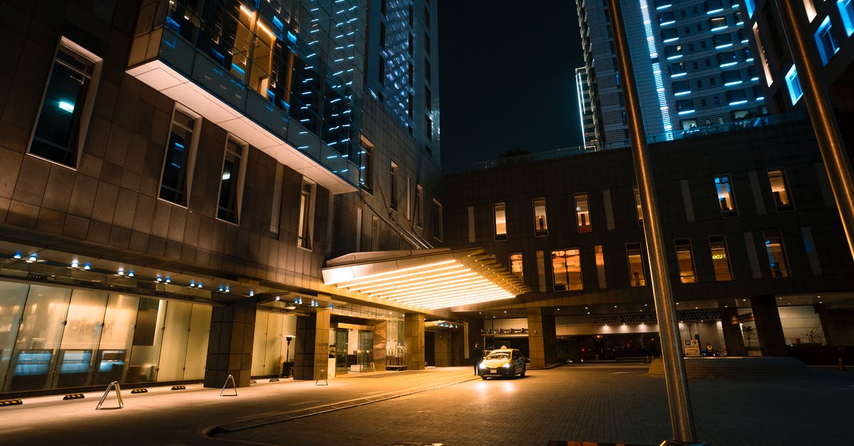 Parking in Prague center - Town with illuminated buildings with windows near parking lot with taxi car near pavement under dark cloudless sky at night