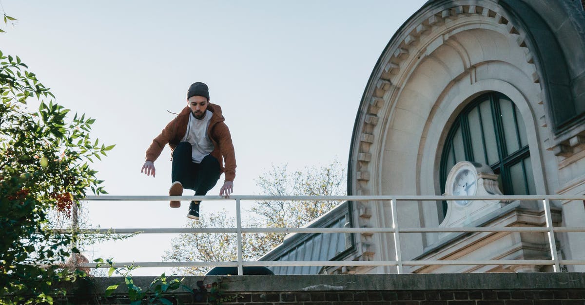 Parkour - Tricking - Free-running in Tokyo? - Young man jumping over railing on building roof