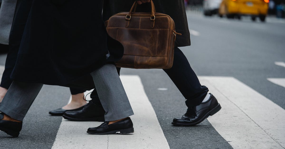 Pedestrian guide to cross the road in London? - Side view of crop unrecognizable coworkers in formal wear with leather briefcase crossing urban road