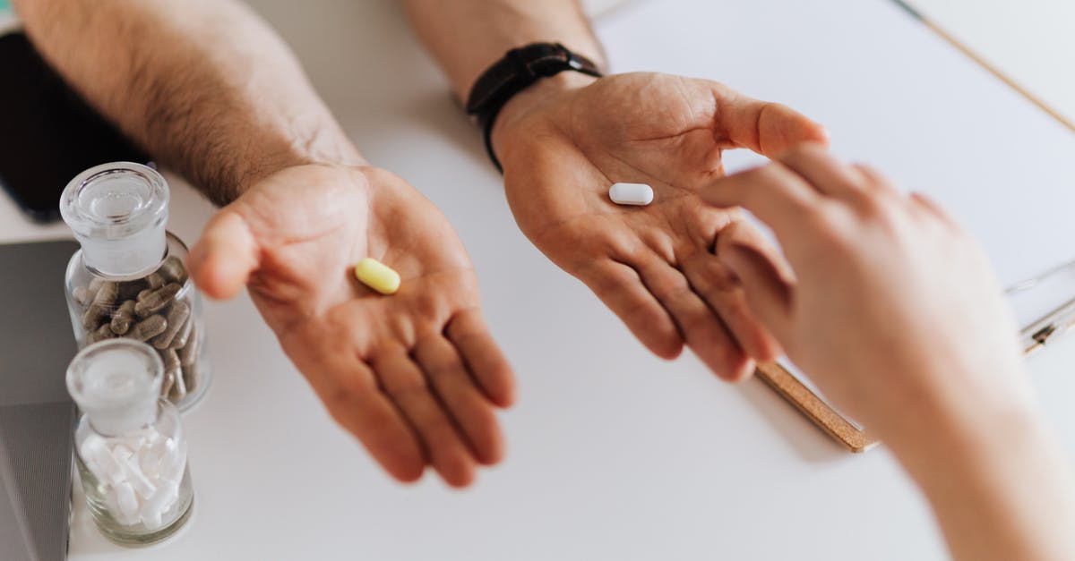 Pharmacy or Doctor visit required in Russia? - From above anonymous female and unrecognizable doctor man giving yellow and white tablets for choosing while working in modern clinic