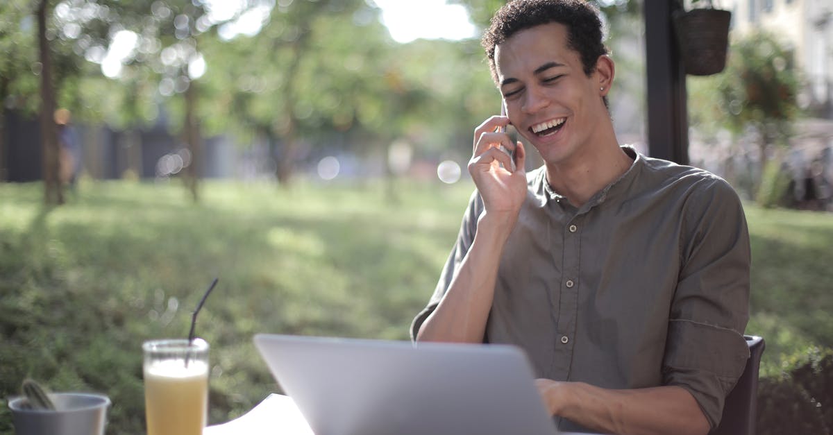 Phone calls within countries in Europe [closed] - Content African American male freelancer wearing casual clothes sitting at table in street cafe with laptop and speaking on cellphone while working on startup