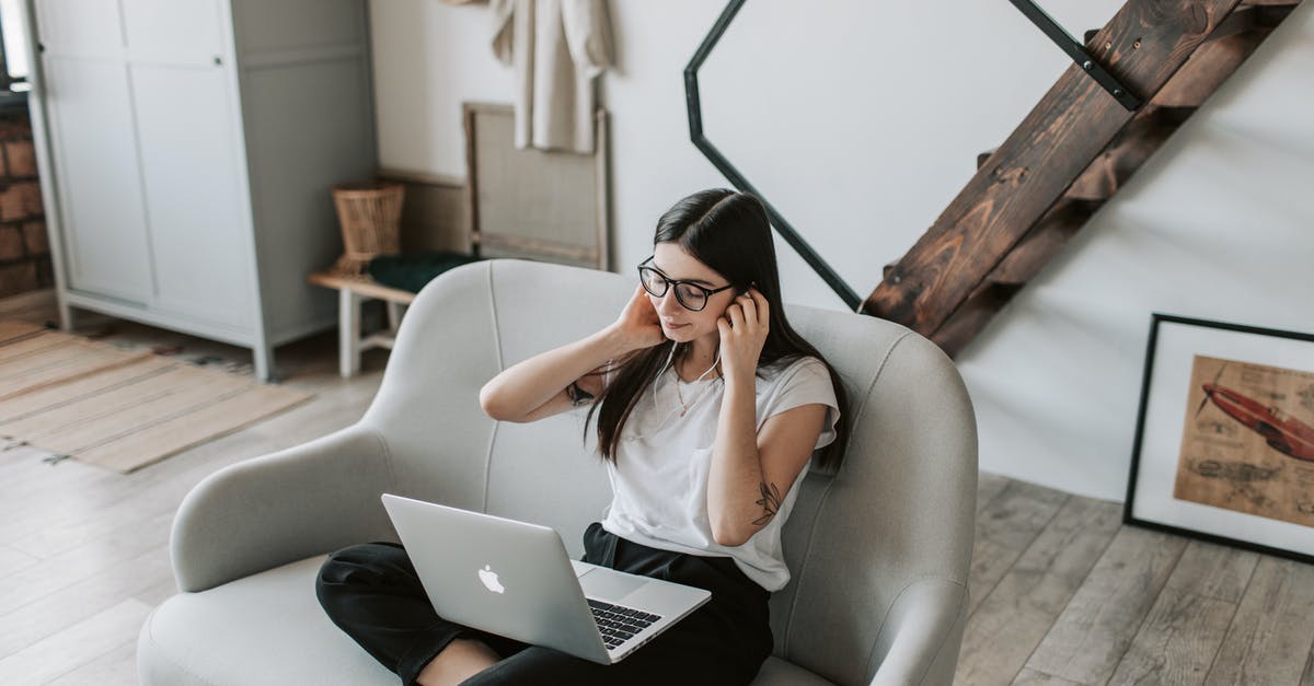 Photographable location from "Gangnam Style" music video - Positive woman using earphones and laptop at home during free time