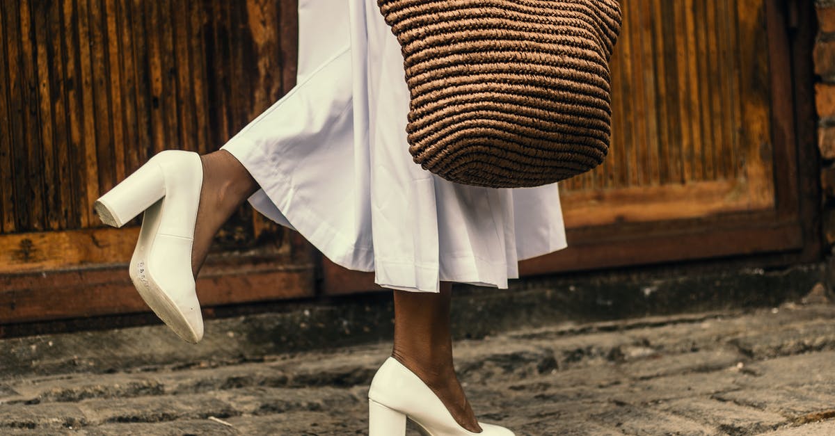 Photoshoot in Durdle Door and Lulworth Cove - Woman Wearing White Dress and White High-heeled Shoes While Walking on Sidewalk