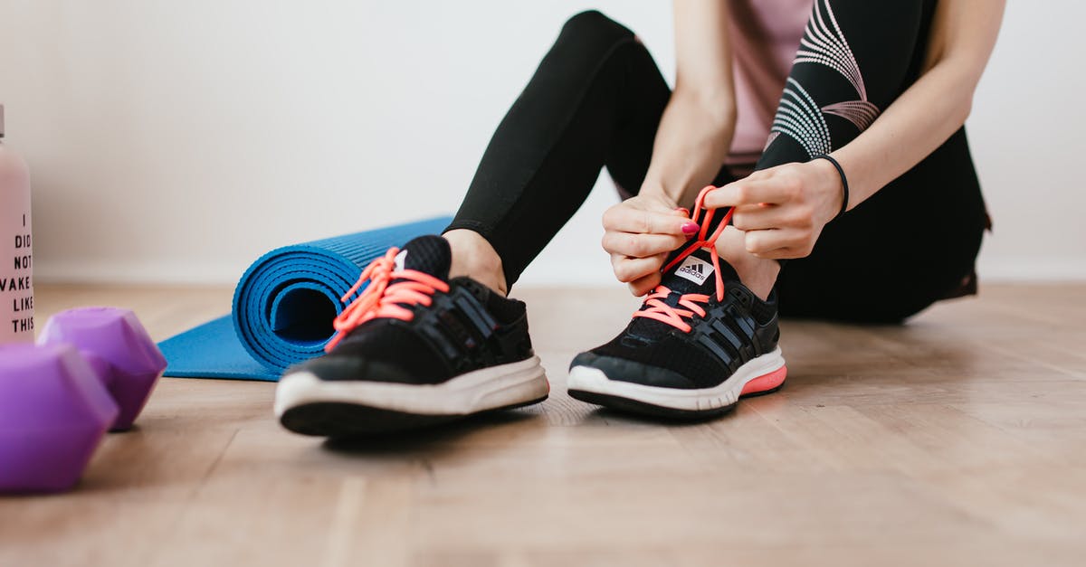 Physical (demanding) activities in Berlin - Anonymous slender female athlete tying shoelaces near sport accessories