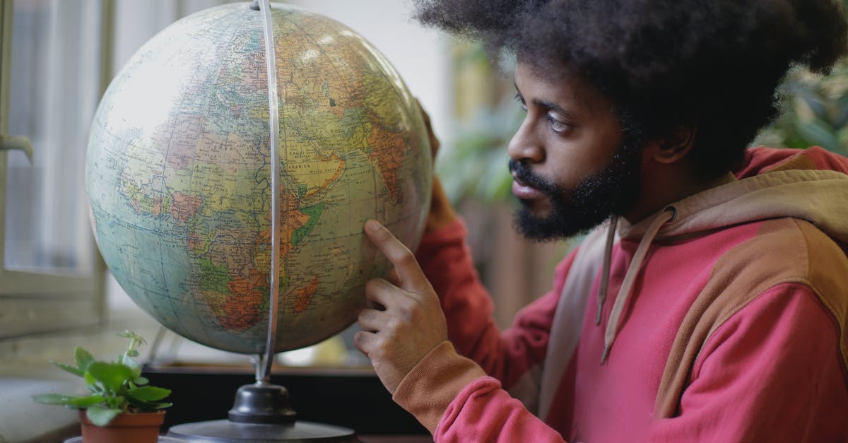 Place on earth with the highest minimum temperature? - Thoughtful young bearded ethnic man with globe sitting at table in modern room