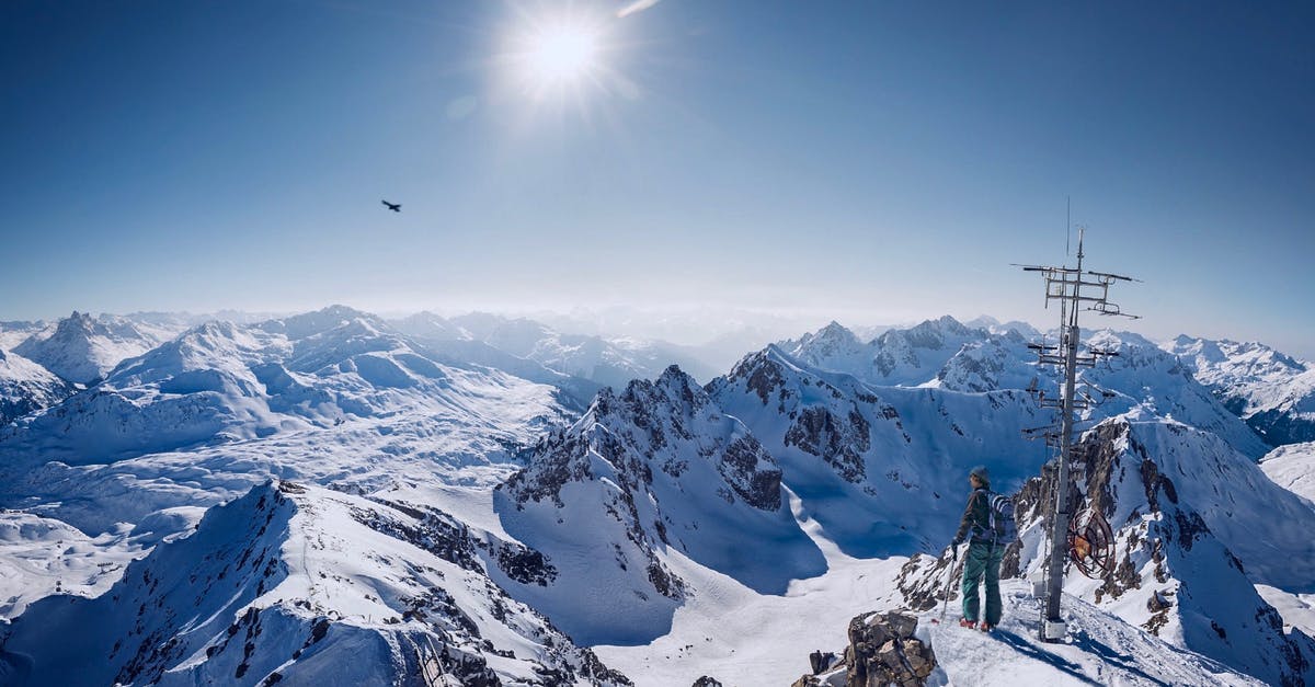 Places in the Alps by sunshine duration - Person on Top of Snow Covered Mountain Under Clear Blue Sky