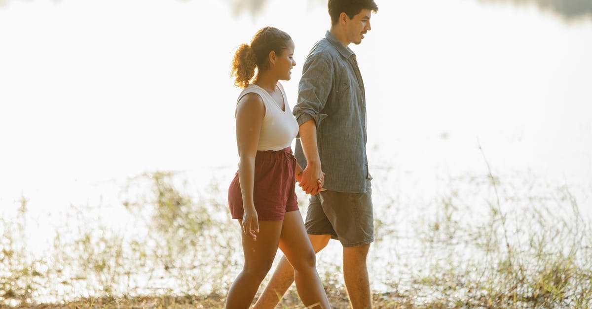 Planning a Swiss hut-to-hut hiking trip in May [closed] - Loving young multiethnic couple holding hands while hiking on lake shore