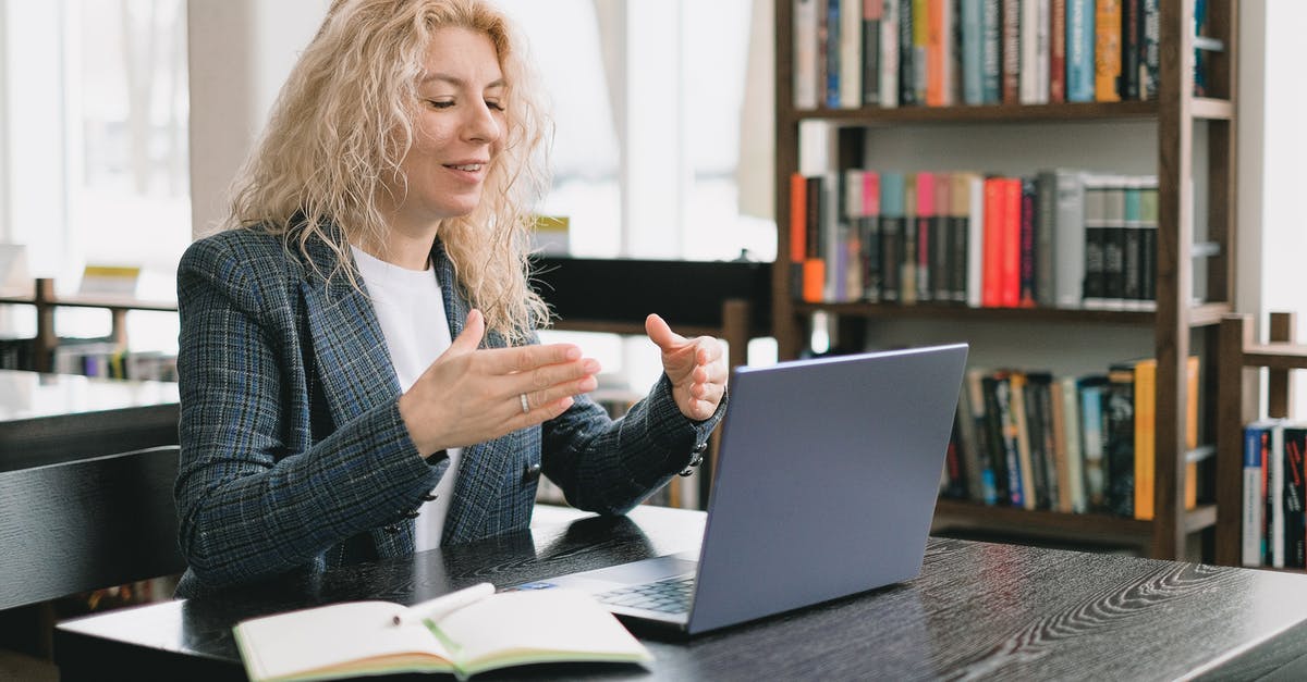 Please explain the local library system in London, England - Smiling woman having video chat via laptop in library