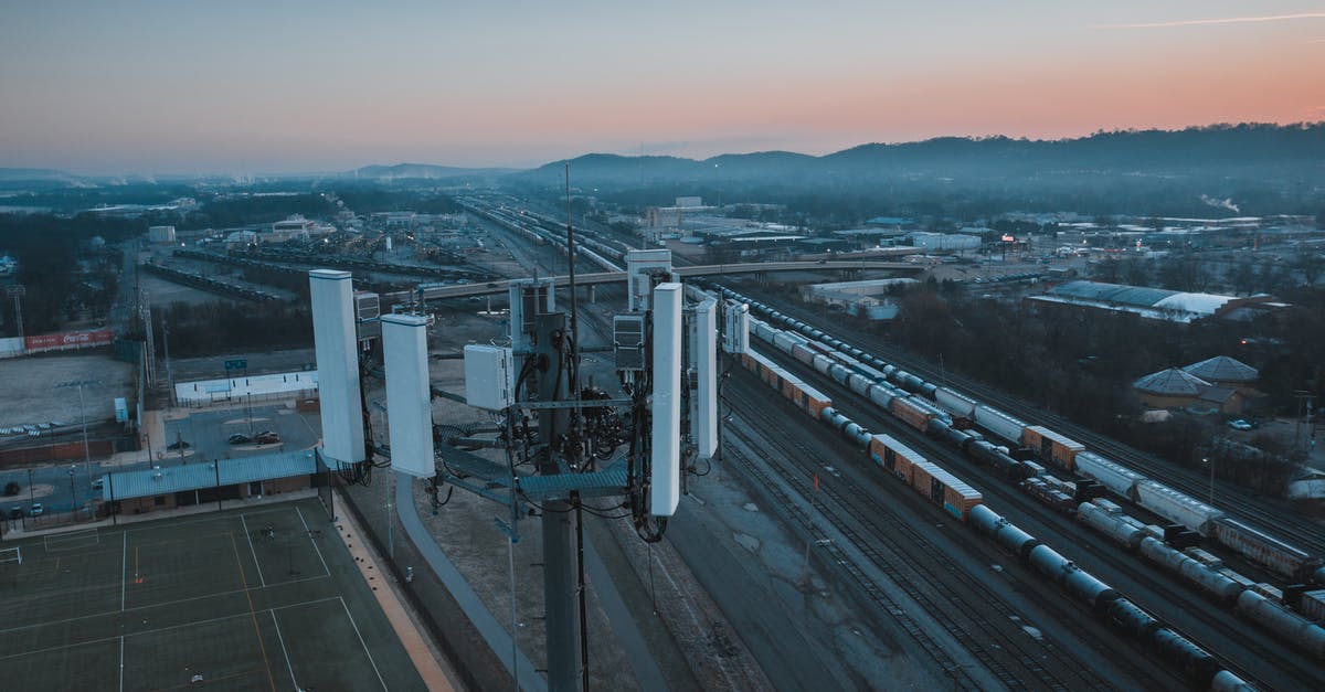 Portugal to USA by cargo ship? - Cell tower in city suburban area with railroad station at sundown