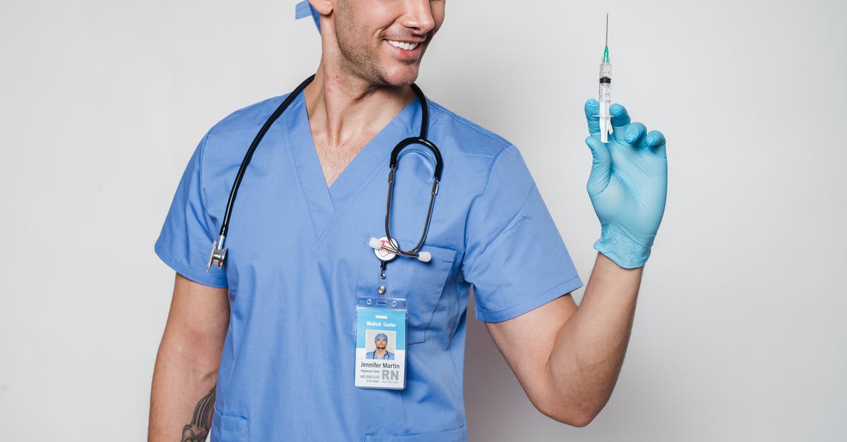 Positive drug test in Singapore: How long do I need to avoid the country? - Smiling male doctor in uniform and gloves with stethoscope holding syringe while standing against white background in clinic