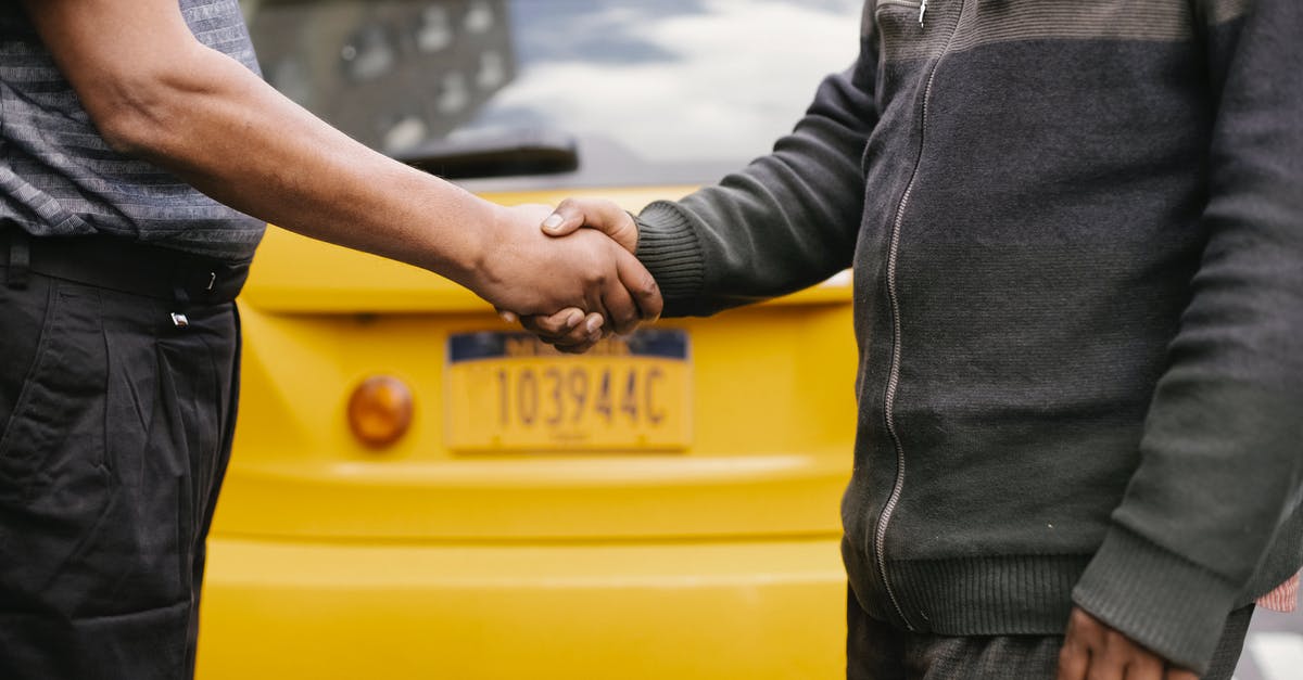 Possible taxi scams if fare is agreed in advance? - Side view of crop ethnic anonymous males shaking hands while meeting each other on street