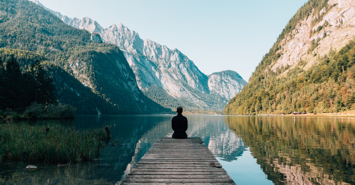 Possible to Travel to A Quiet Place? - A Person Sitting on Wooden Planks Across the Lake Scenery