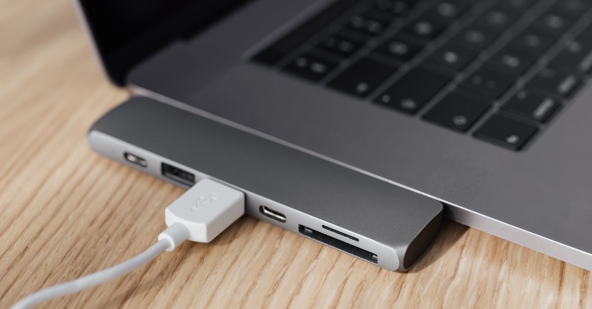 Power plugs in Sri Lanka - High angle of modern space silver laptop with USB type c multiport hub with plugged white cable placed on wooden table