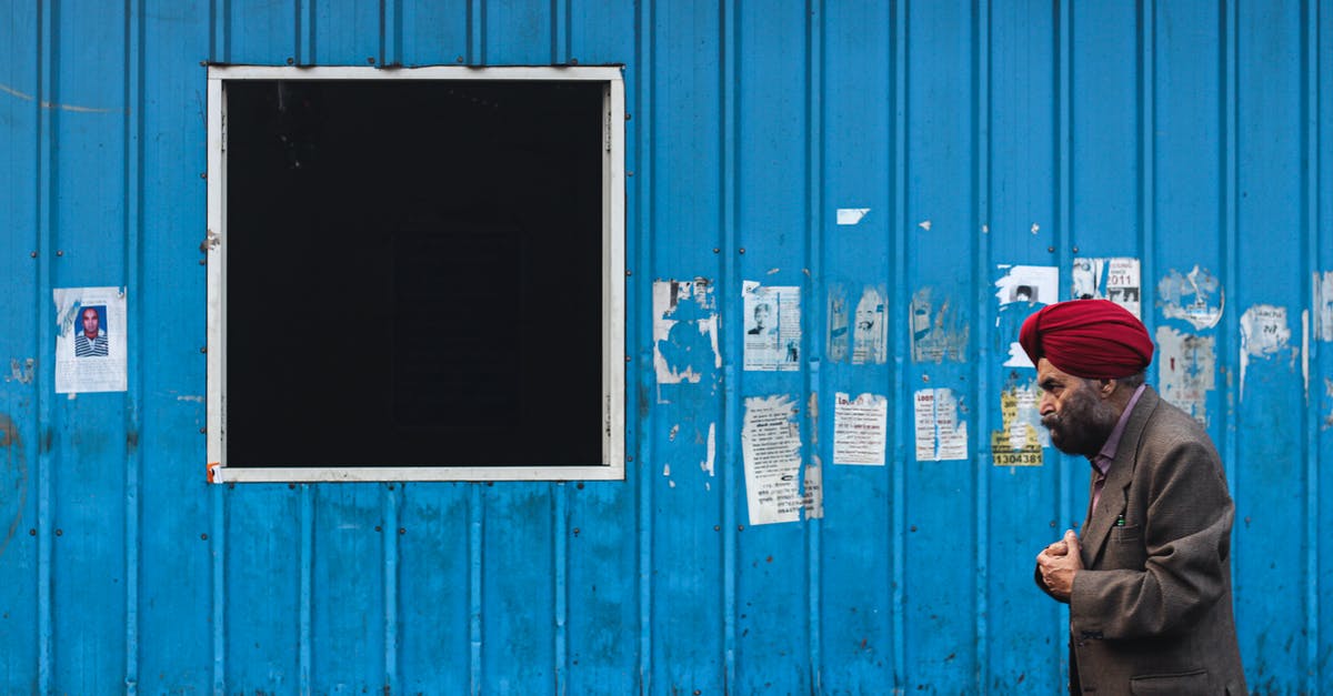 Practical aspects of security when travelling in India - Man in Black Jacket Standing Beside Blue Wooden Door