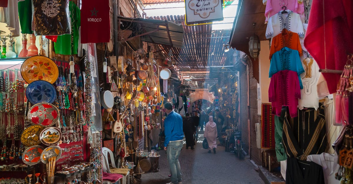 Precautions and Customs to observe when traveling in Morocco - Unrecognizable people walking in local bazaar near stalls with various goods and souvenirs and traditional clothes on sunny day in Marrakesh